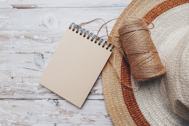 a skein of twine with a notepad for text and a hat on a wooden surface