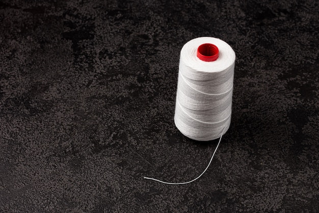 Photo a skein of white thread on a black background. copyspace