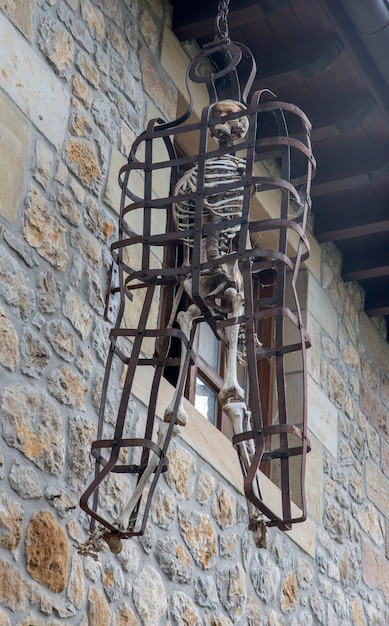 Скелет, висящий в типичной средневековой клетке
