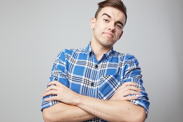 skeptical guy dressed in a plaid shirt is on a white background in the studio .