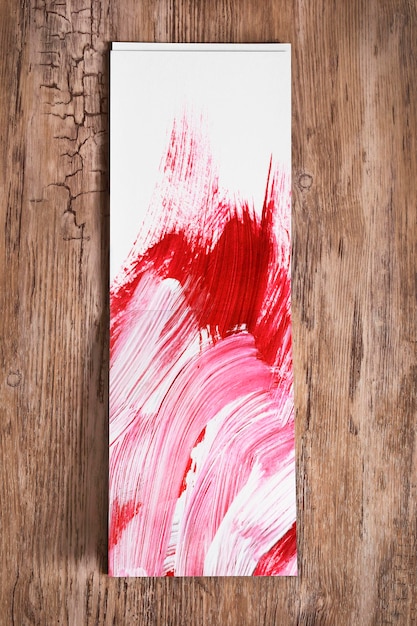 Фото Альбом для рисования с абстрактными красными и белыми рисунками гуаши на деревянном фоне