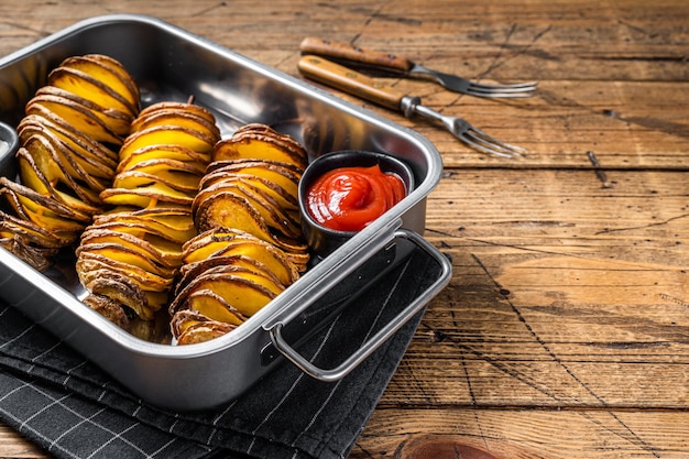 Skewered fried tornado or twist potatoes with ketchup sauce Wooden background Top view Copy space