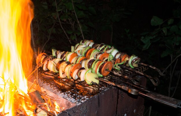 Skewers of diced vegetables rings on the grill grate