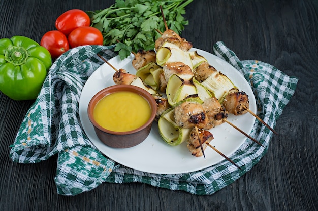 Skewers on a skewer with zucchini with sauce. Dark wooden background.