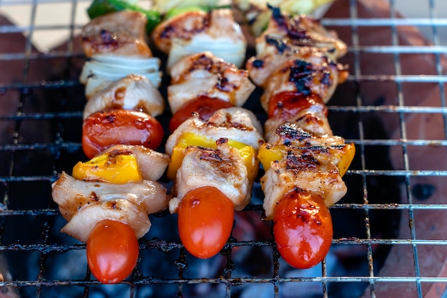 Skewers with pieces of grilled barbecue green bell pepper red\
tomato and meat for sell in street market thailand closeup