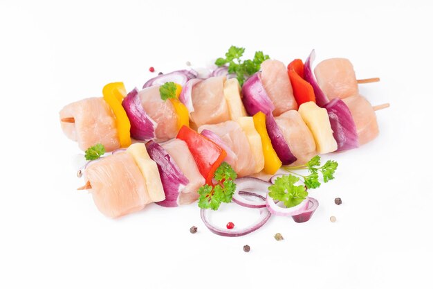 Skewers with pieces of raw meat red yellow and green pepperraw pieces of chicken skewers with pepper