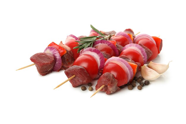 Skewers with raw meat and vegetables isolated on white table