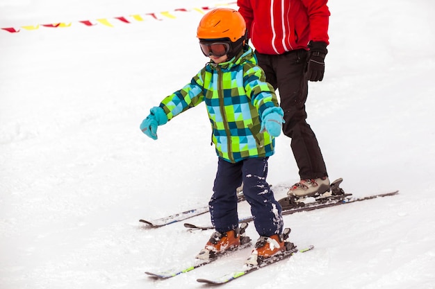 Инструктор по лыжам учится кататься на лыжах Little Child Kid. Лыжная школа. Зимние лыжные каникулы.