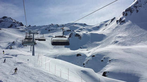 Ski-lift over besneeuwde bergen tegen de lucht