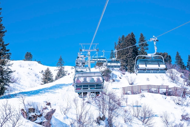 澄んだ青い空を背景に、風光明媚な雪に覆われた山の上のスキーリフト