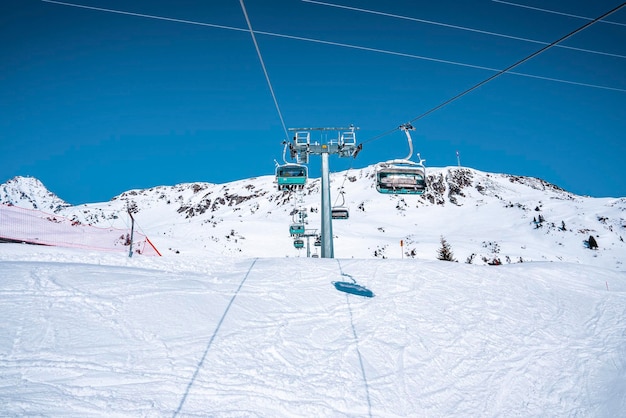 Ski lift on snow covered landscape against clear blue sky