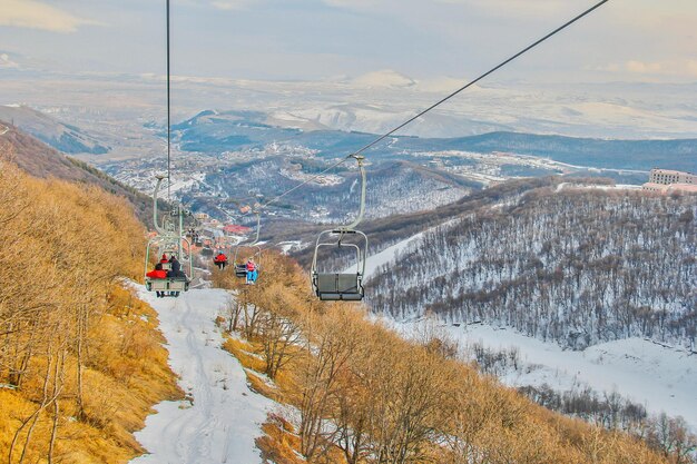 空に向かって雪で覆われた山をスキーリフトで乗る