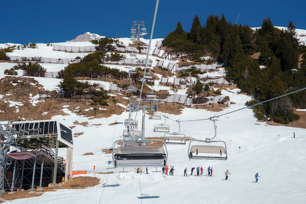 Ski lifts with tourists on snow covered mountain