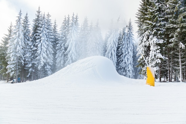 Ski resort snow guns running in the snow and trees inii winter holiday in the mountains of skiing and snowboarding