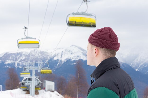 Ski resort. The young man admires nature, stands against the mountains.