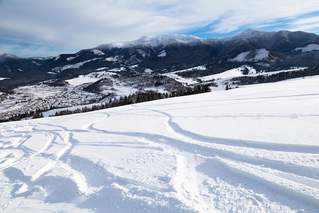 Горнолыжный склон с лыжными трассами, красивый вид на зимний день с вершины горы в долину
