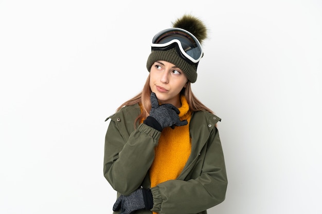 Skiër blanke vrouw met snowboard bril geïsoleerd op een witte muur en opzoeken