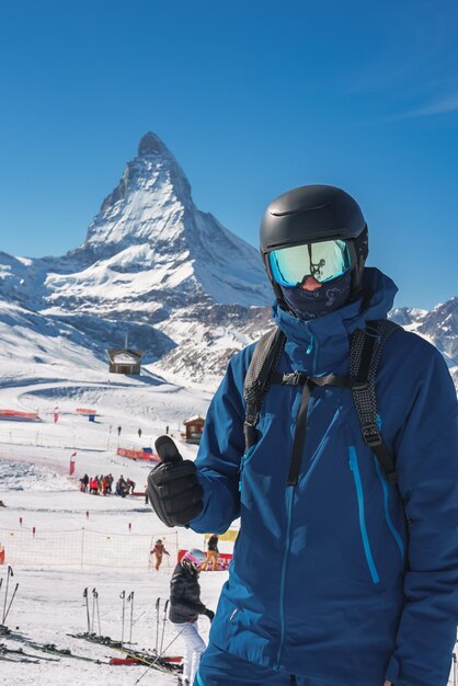 Photo a skier in a blue jacket with a mountain in the background