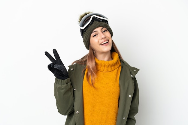 Skier caucasian woman with snowboarding glasses isolated on white smiling and showing victory sign