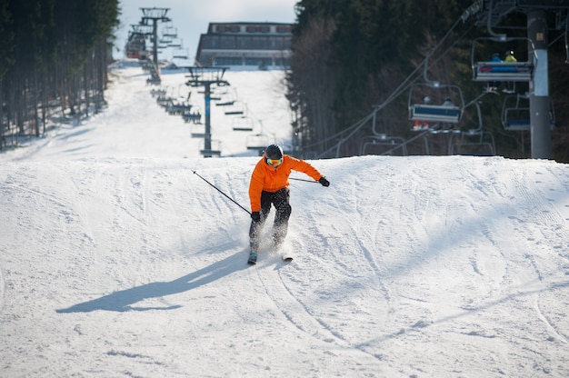 Skiër die bergaf na het springen in skigebied tegen skilift en sneeuwhelling ski? En