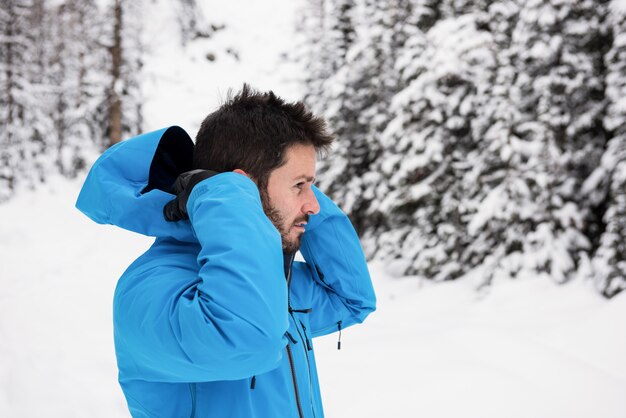 Skiër die jas met een kap op sneeuwbergen draagt