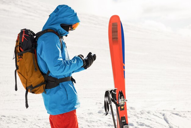Skiër die mobiele telefoon op de sneeuwbergen met behulp van