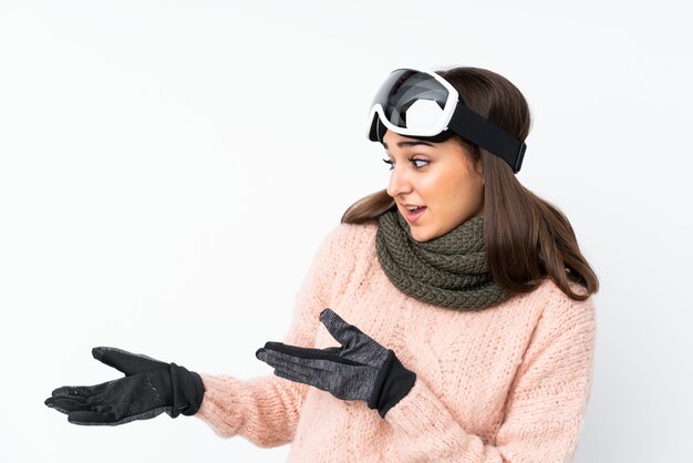 Skier girl with snowboarding glasses over isolated white wall with surprise facial expression