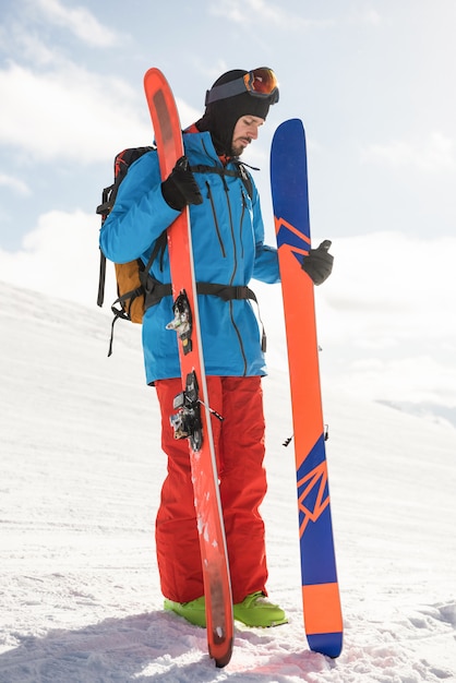 Skier holding ski on the snowy mountains