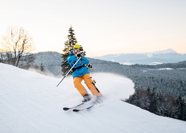 写真 雪粉のスキーヤーの男は山の斜面にブレーキをかけます