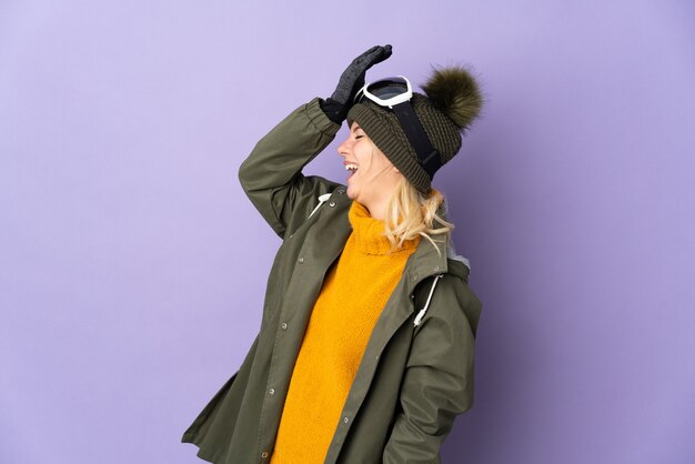 Skier Russian girl with snowboarding glasses isolated on purple background has realized something and intending the solution
