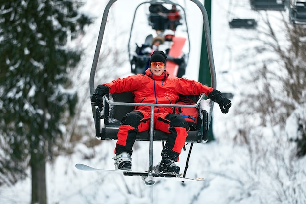 Skier sitting at ski lift in high mountains during sunny day. Winter sport and recreation, leisure outdoor activities.