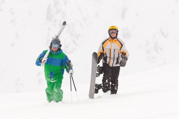 Skier and snowboarder carrying gear