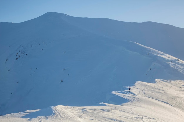 스키어는 큰 산의 눈 코니스 가장자리에 서 있습니다.
