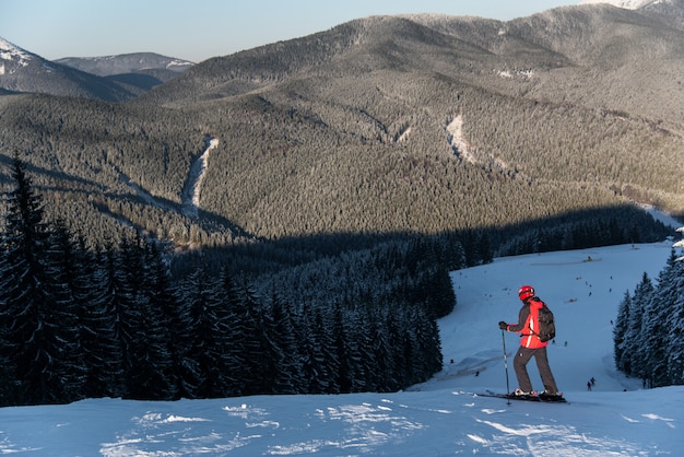 Skier at the top of descent enjoying mountains and forests