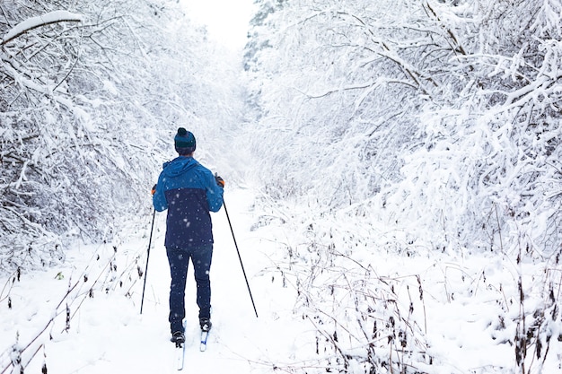 Skier in windbreaker and hat with pompom with ski poles in his hands