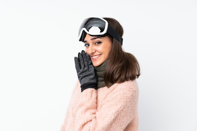 Skier woman with snowboarding glasses over isolated white wall whispering something