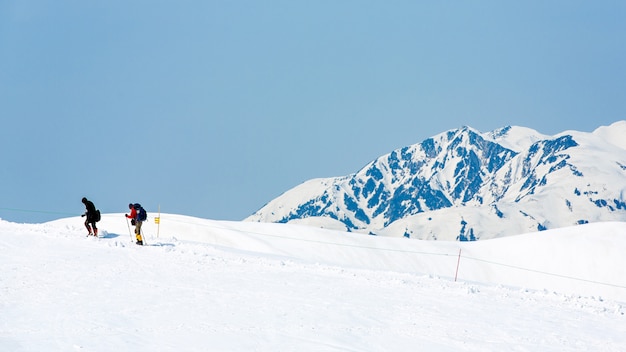 Skiërs die op sneeuw behandelde bergketens lopen