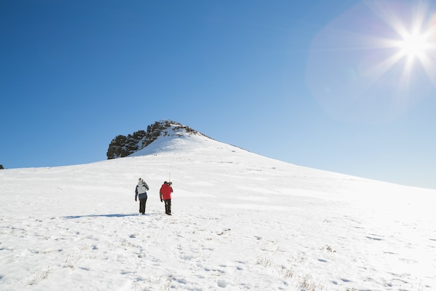 Skiërs die op sneeuw op een zonnige dag lopen