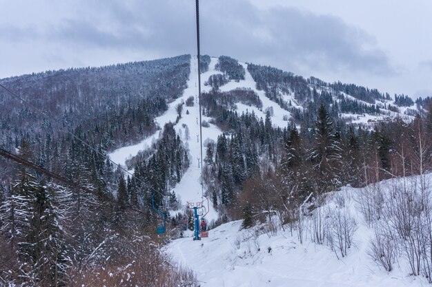 Skiers on a ski lift on snowy mountainside