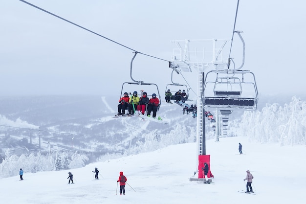 Skiers skiing downhill and taking a chair lift in a hilly winter landscape