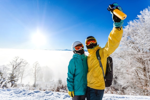 Skiers taking picture of themselves with smart phone over a mountain