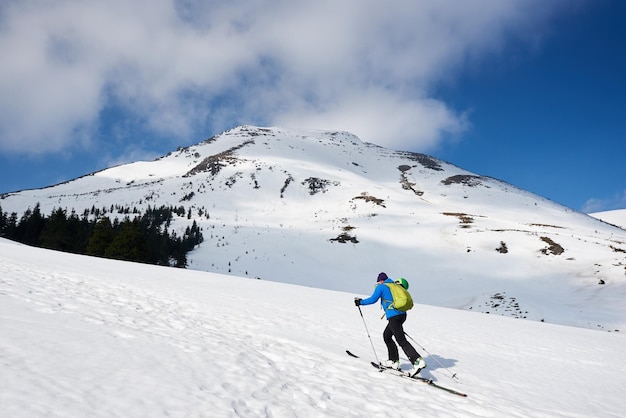Skiërtoerist met rugzak op achtergrond van heldere blauwe hemel en mooi bergpanorama