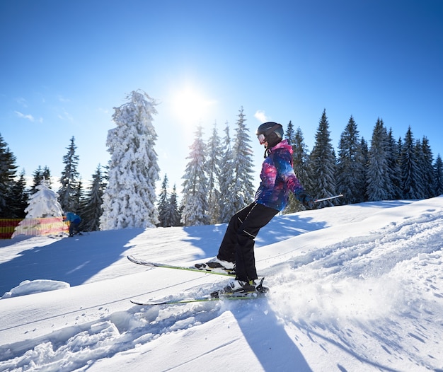 Skiing from mountain slope. Woman skier falling on snow. Concept of active winter vacation at resort. Side general view.