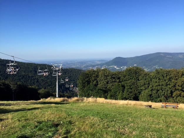 Skilift over een grasrijke heuvel tegen het landschap