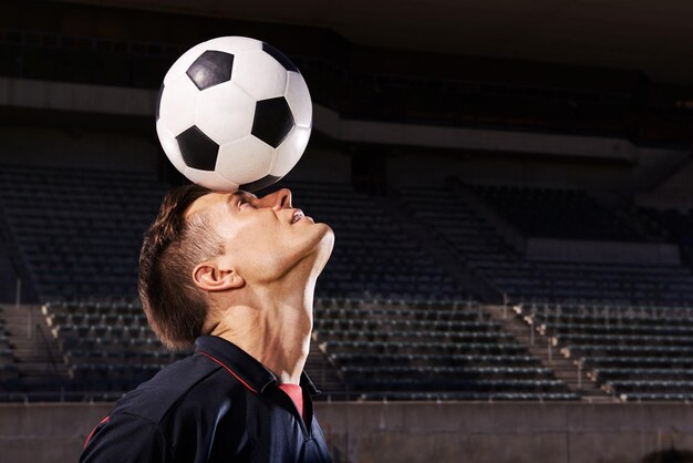 スキルとバランス頭の上のボールのバランスをとる若いサッカー選手のショット