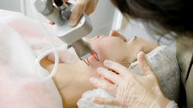 Skilled beauty salon therapist in sterile gloves makes laser hair removal procedure on patient face extreme close-up