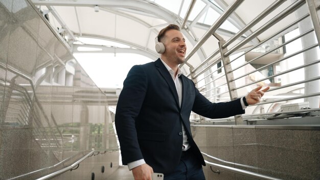 Skilled business man dance to music from headphone at modern corridor Urbane