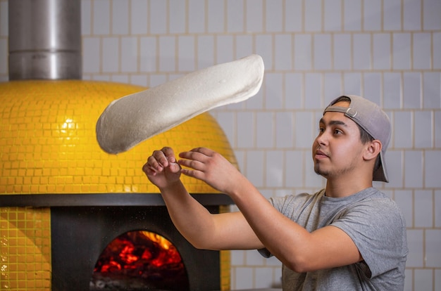 Skilled chef preparing dough for pizza rolling with hands and throwing up