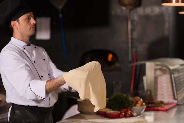 Skilled chef preparing dough for pizza rolling with hands and throwing up