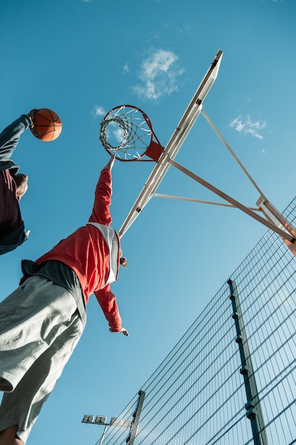 Skilled player. Nice athletic man jumping up while touching the basketball basket